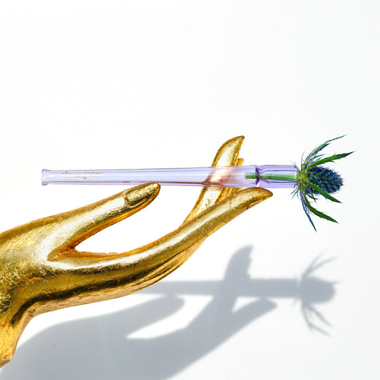 Gold hand statue holding a Cruella joint holder made from transparent purple glass